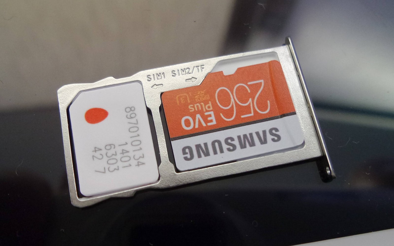 Sim card and samsung 256gb evo plus memory card resting in a phone's tray